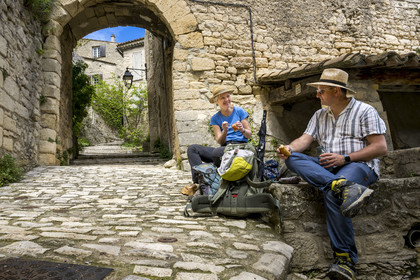 France, Vaucluse (84), Dentelles de Montmirail, le village perché de Crestet, pique nique de randonneurs devant la porte du village