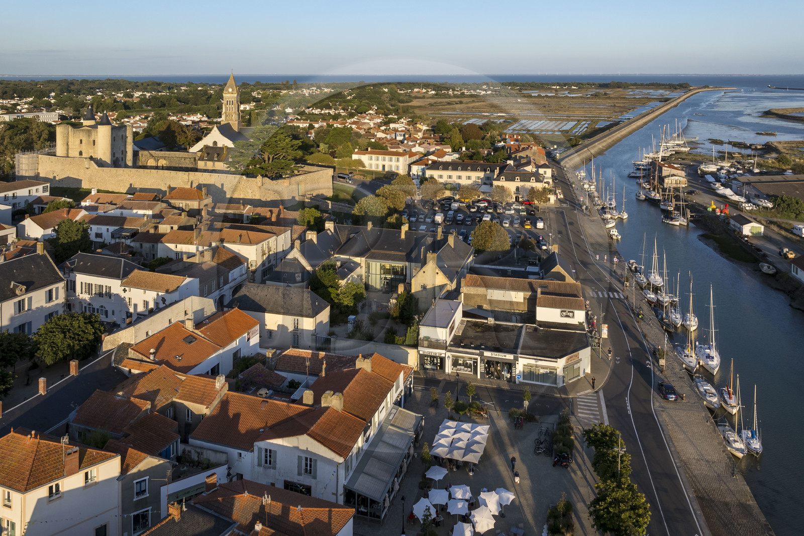 France, Vendée, Noirmoutier island, Noirmoutier en l’Ile, beaching port in Etier du Moulin, the medieval castle and the Saint-Philbert church in the background (aerial view)