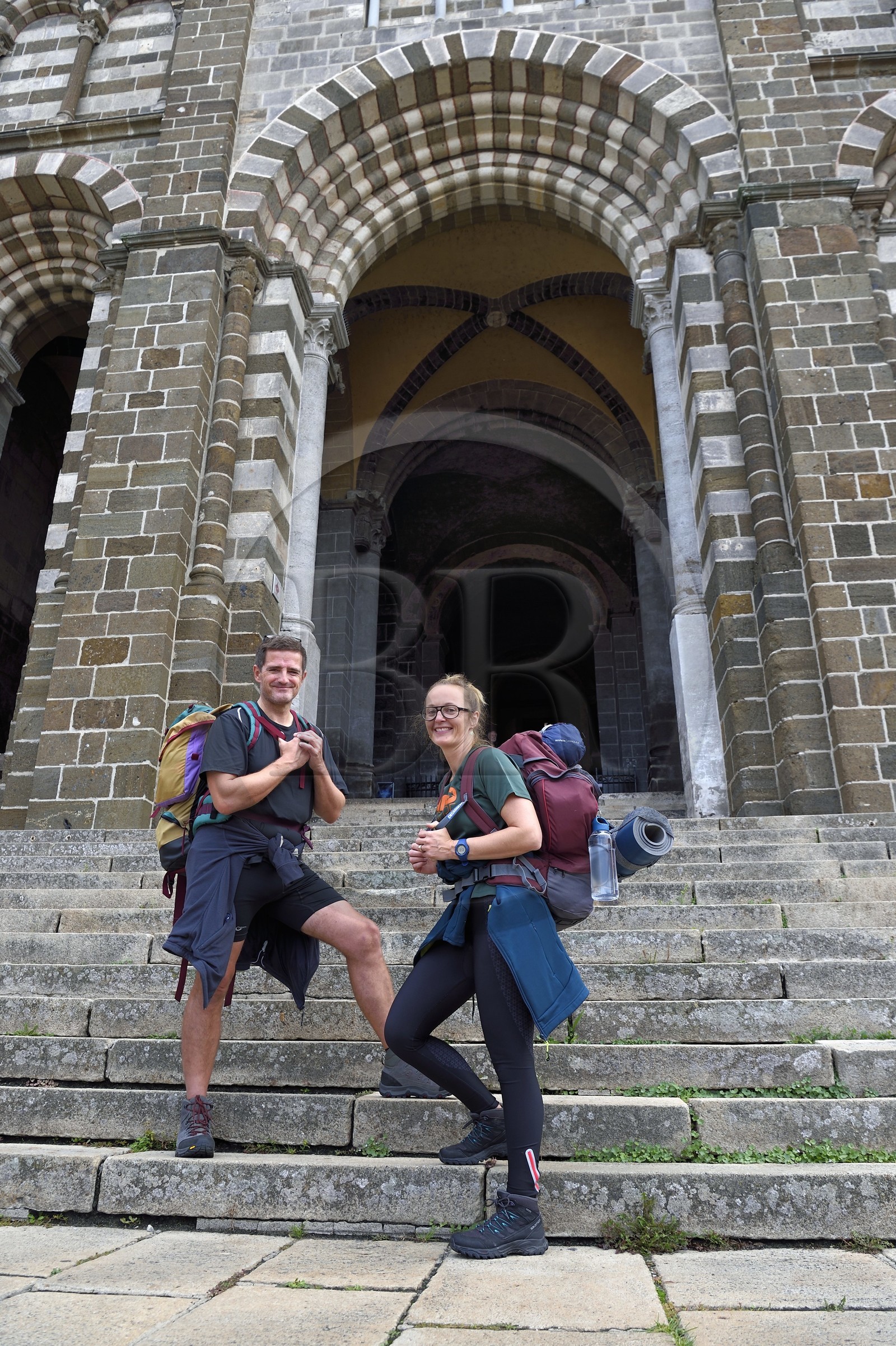 France, Haute Loire, Le Puy en Velay, a couple of pilgrims on the route of Santiago de Compostela in front of the porch of the 12th century Our Lady (Notre-Dame-de-l'Annunciation) cathedral listed as World heritage by UNESCO