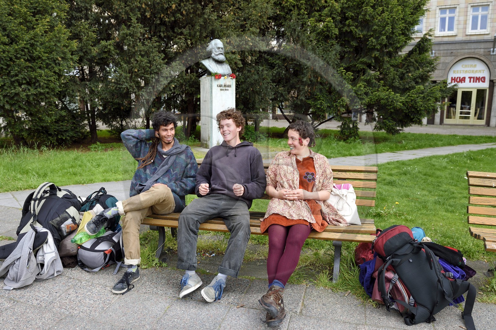 Germany, Berlin, Karl-Marx Allee, young travelers in front of the bust of Karl Marx