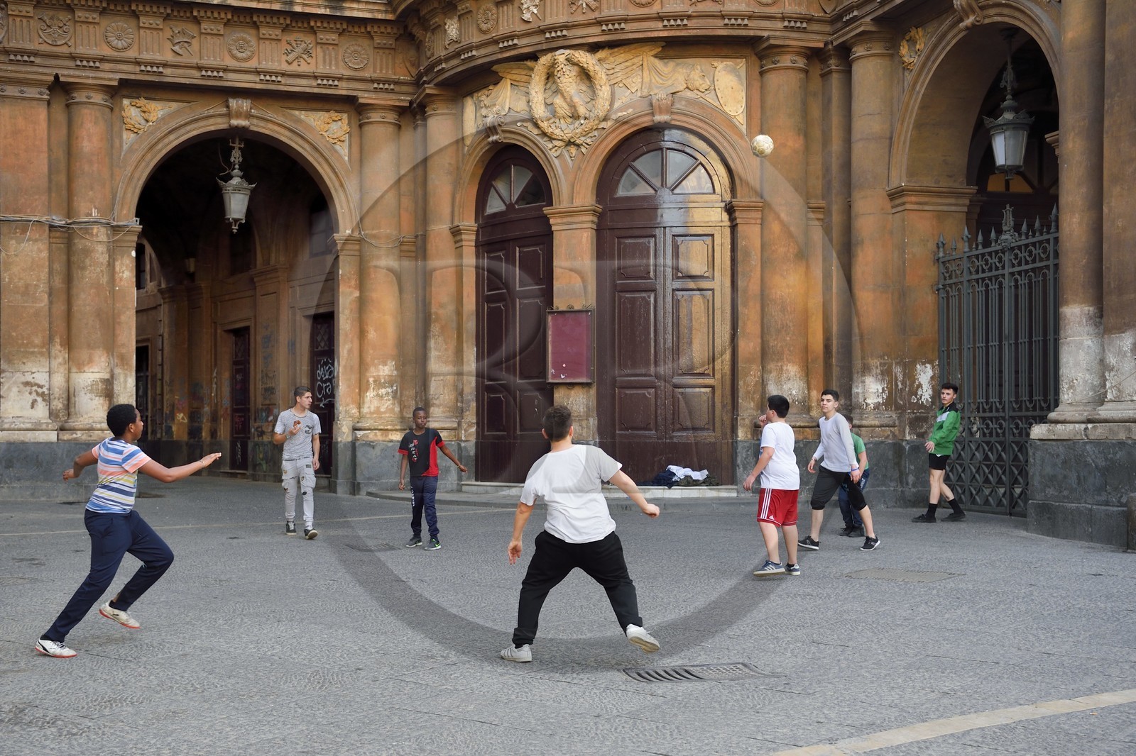 Italy, Sicily, Catania, Baroque city listed as UNESCO World Heritage, children playing football in front of the Teatro Massimo Vincenzo Bellini opera house