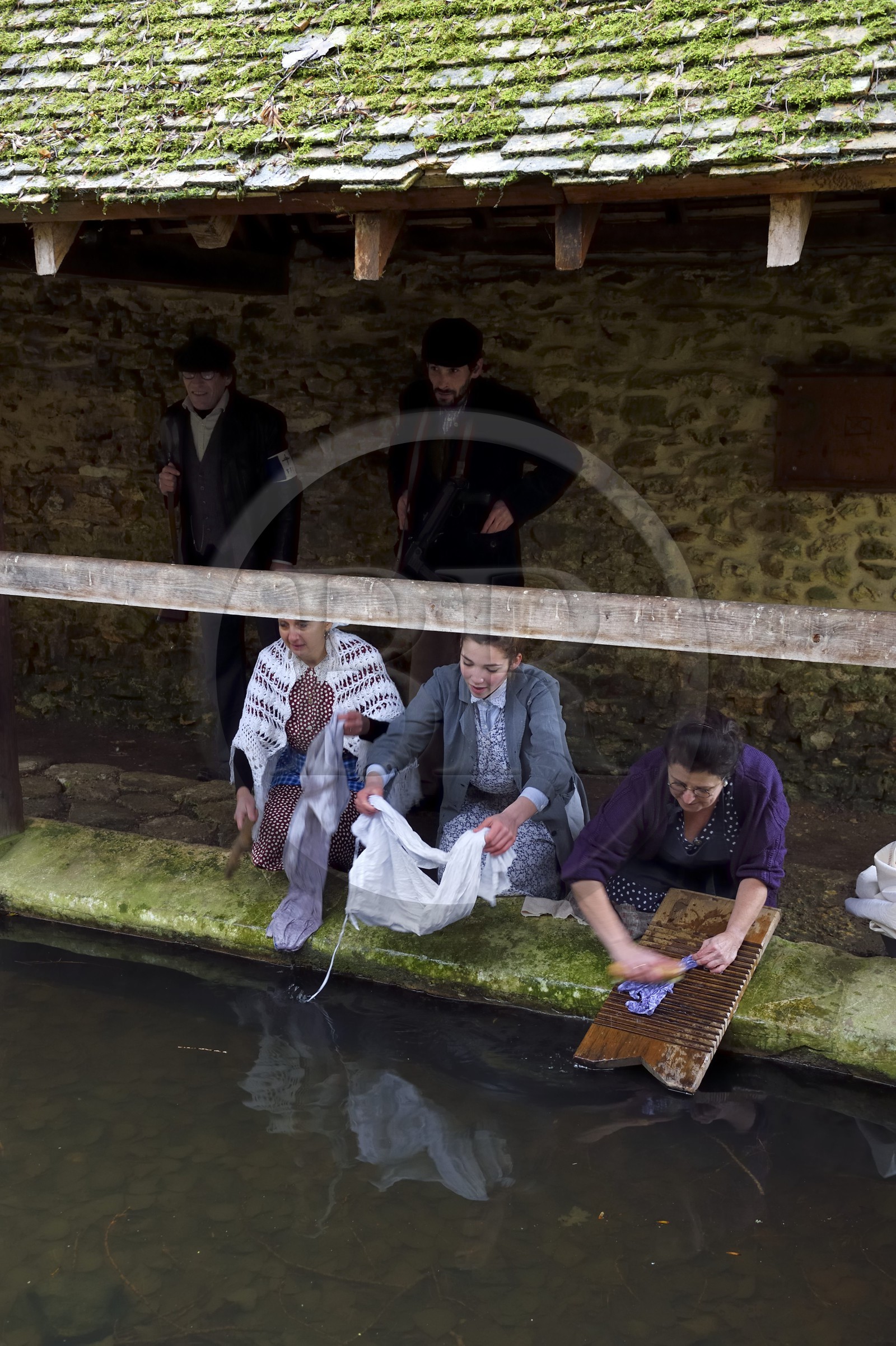 France, Eure (27), lavoir de Sainte-Colombe-prés-Vernon, Allied Reconstitution Group (association de reconstitution historique de la 2éme Guerre Mondiale US et Maquis), les reconstitueurs montrant trois femmes lavant de linge au lavoir dans les années 1940 et deux maquisards des Forces françaises de l'intérieur (FFI) en arrière plan
