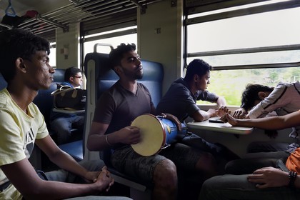 Sri Lanka, Central Province, young people playing the bongos during their journey in the popular scenic train through the tea growing hill country between Hatton and Badulla, here between Talawakele and Great Western
