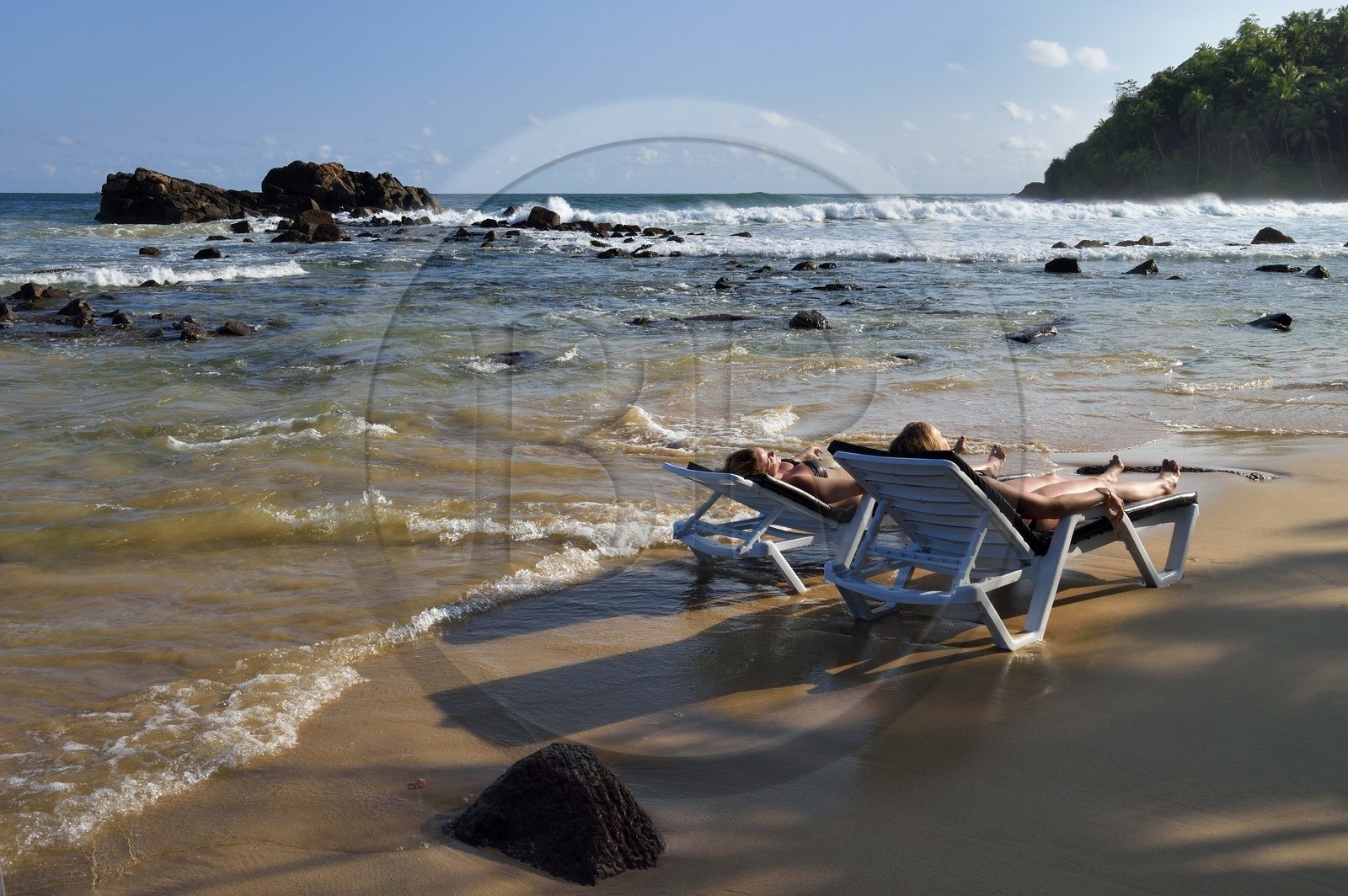 Sri Lanka, Southern Province, Matara district, Weligama, Mirissa Beach, women sunbathing on a lounge chair feet in the water