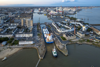 France, Loire Atlantique, Saint Nazaire, The General Cargo Rotra Mare transports sections of wind turbine masts and enters the port's wet dock (in the background) via the south lock, which was also the site of Operation Chariot launched in 1942 by the British (aerial view)