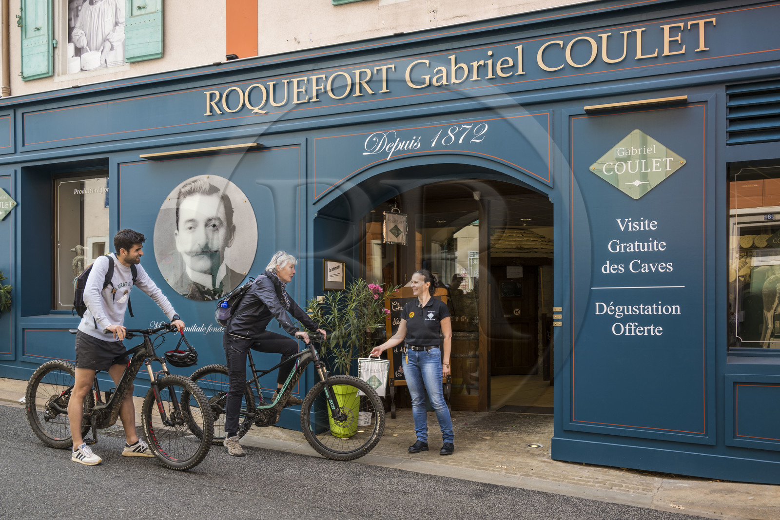 France, Aveyron, Grands-Causses Regional Nature Park, Roquefort sur Soulzon, cyclists on the Brebis Cyclette tourist cycle route in the Pays de Roquefort, head office and shop of the Gabriel Coulet Roquefort cheese maturing cellar