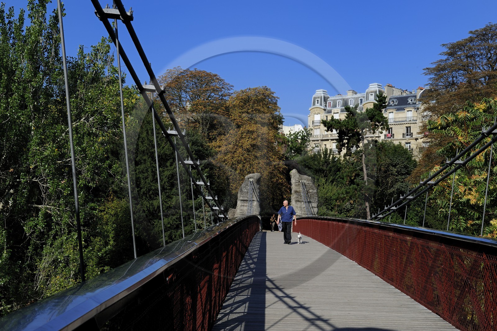 France, Paris (75), parc des Buttes Chaumont, la passerelle suspendue et les immeubles haussmanniens de la rue Manin