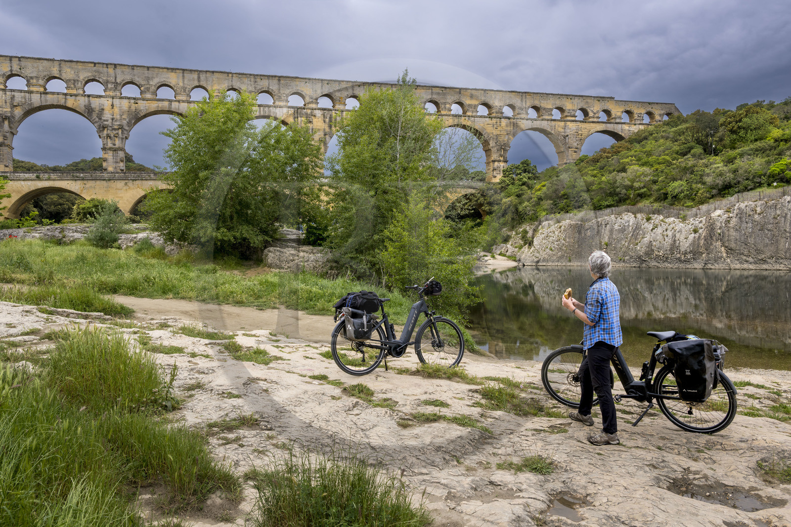 France, Gard, the Pont du Gard listed as World Heritage by UNESCO, Grand Site de France, cyclist taking a break in front of the Roman aqueduct bridge spanning the Gardon river